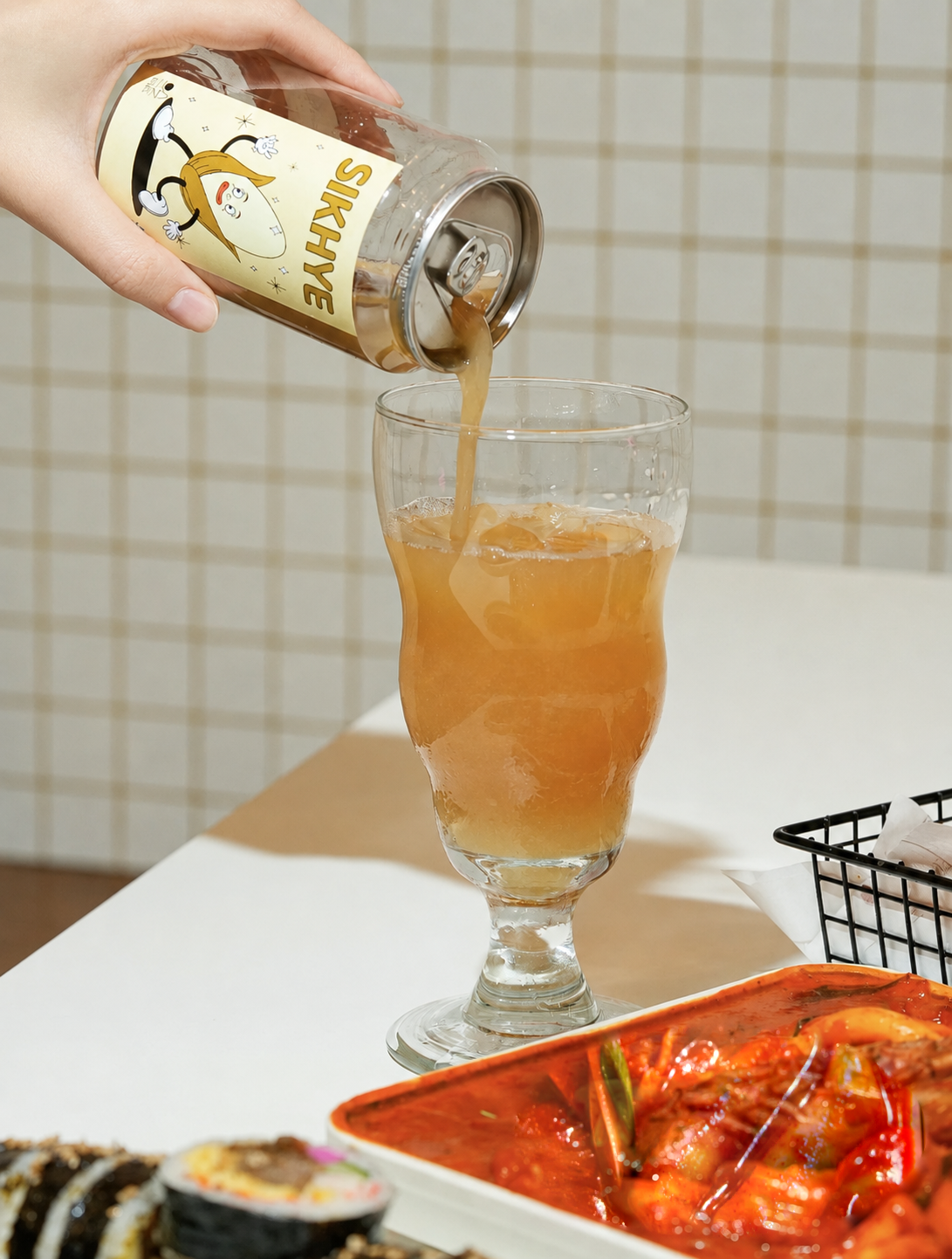 ESSEL Sikhye being poured with short natural matte nails and original tteokbokki visible